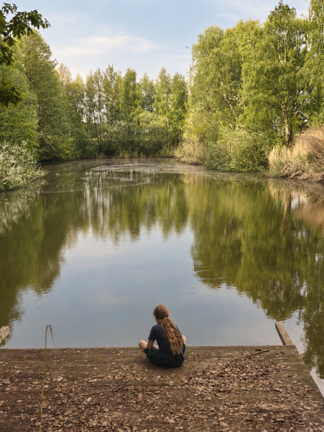 Joris sitzt ruhig am Steg und blickt auf den See